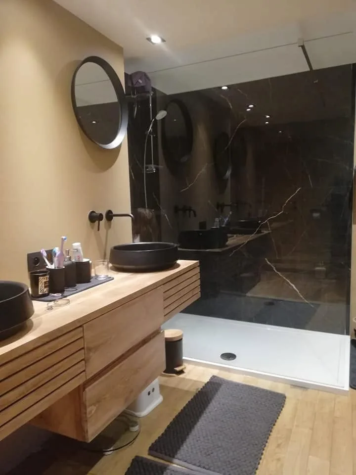 Salle de bains avec meubles en bois, vasques noires et douche marbre