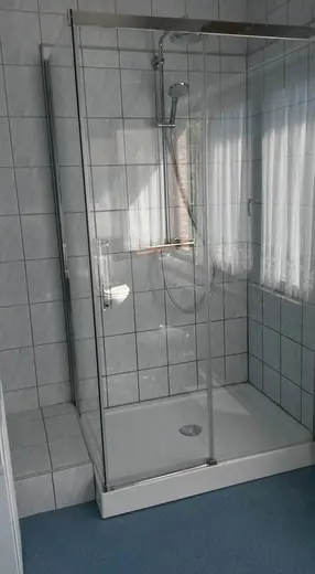 Cabine de douche avec parois vitrées, carrelage clair et receveur blanc