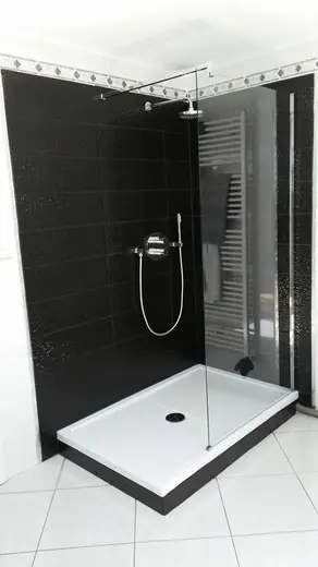 Douche avec carrelage noir, paroi vitrée transparente et receveur blanc